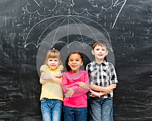 Three children standing under drawn umbrella
