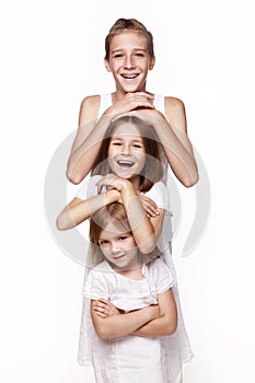 Three children in the studio on a white background, a brother and two sisters laugh