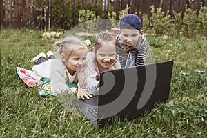 Kids playing computer games lying on the grass