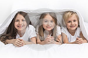 Three children under blanket