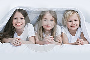 Three children under blanket