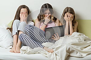 Three children under the impression of the video at home in the bed, Closed the face from fear with their hands