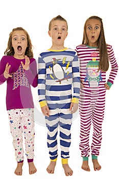 Three children wearing winter pajamas with a startled facial exp