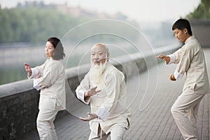 Three Chinese People Practicing Tai Ji Outdoors