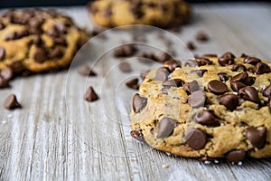 Three chocolate chip cookies with chunks and chocolate on a wooden table