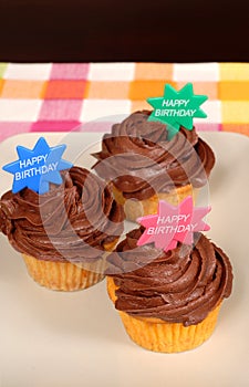 Three chocolate frosted cupcakes with