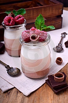 Three chocolate mousse dessert in a glass jar garnished with raspberries