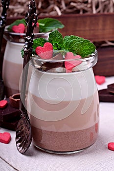 Three chocolate mousse dessert in a glass jar garnished with sugar hearts