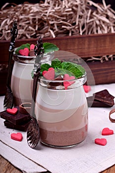 Three chocolate mousse dessert in a glass jar garnished with sugar hearts