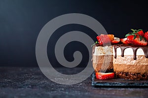 Three chocolates cake with chocolate drips on a black background. Layered cake with milk, black and white chocolate souffle