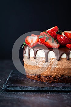 Three chocolates cake with chocolate drips on a black background. Layered cake with milk, black and white chocolate souffle