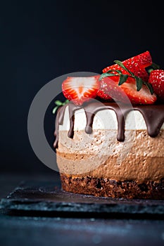 Three chocolates cake with chocolate drips on a black background. Layered cake with milk, black and white chocolate souffle