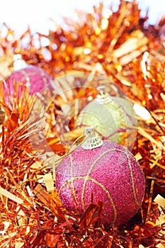 Three Christmas baubles with orange tinsel