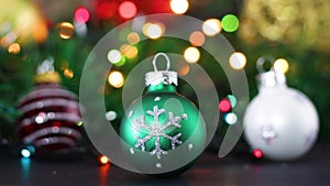 Three Christmas ornaments, green, red and white with blinking lights
