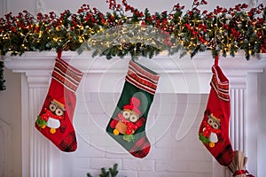Three Christmas socks decorated with owl figures hanging on a shelf under advent garland photo