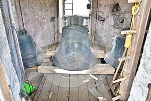 Three church bells rest on a wooden floor within the building