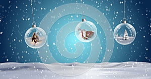 Three clear Christmas baubles dangling against snowflakes falling on snow landscape