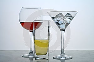Three clear crystal glasses of different shape located at the empty background. Beautiful cocktail set with ice.
