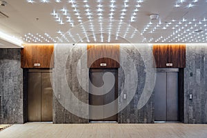 Three closed elevators in modern hotel lobby