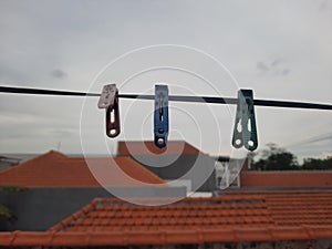 three clothspin hangin on a wire in the cloudy sky