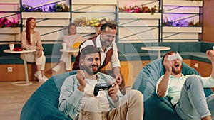 Three co- workers are playing video games and enjoying each-others company while sitting on bean bag chairs, three women