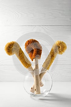 Three coconut scrapers for washing dishes in a glass vase.