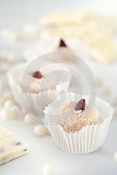 Three coconut truffles topped with almonds, amidst white chocolate chips and a nutty bar