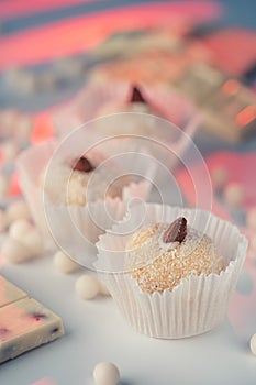 Three coconut truffles topped with almonds, amidst white chocolate chips and a nutty bar