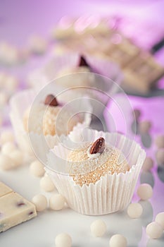 Three coconut truffles topped with almonds, amidst white chocolate chips and a nutty bar