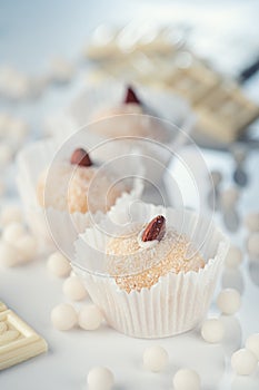 Three coconut truffles topped with almonds, amidst white chocolate chips and a nutty bar