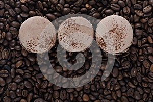 Three coffee biscuits lie in a row in the center on a grain coffee background