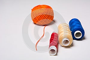 Three coils of multi-colored thread and a hank of orange