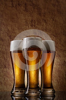 Three cold Beer into glass on a old stone