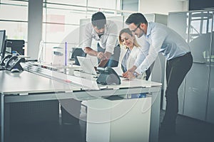 Three colleague in office using computer and checking document.
