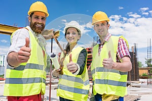 Three colleagues in a construction team showing thumbs up