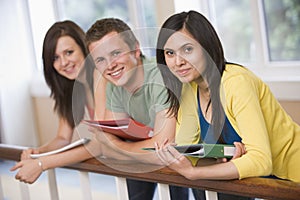 Three college students leaning on banister