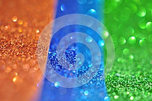 Three color abstract bokeh with orange, blue and green on glittering background.