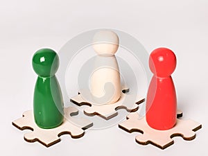 Three color wooden figures on jisaw puzzle pieces against white background.