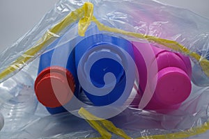 Three colored detergent containers inside a plastic bag. Separate waste collection concept
