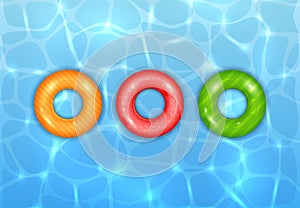 Three Colored Swim Rings on Water Background