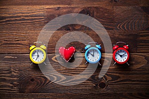 Three colorful alarm clocks and heart shape