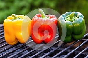 three colorful bell peppers on a charcoal grill