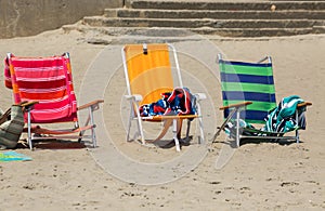 Three colorful chairs on the sand, near the beach