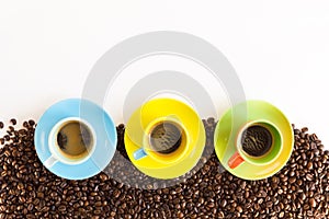 Three colorful coffee cups on group of coffee beans