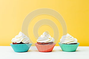 Three colorful  cupcakes on a yellow background