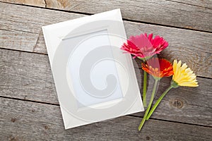 Three colorful gerbera flowers and photo frame