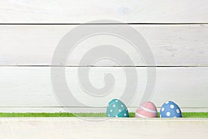 Tre colorato manualmente pasqua uova diventare sul verde prato coperto barriera sul bianco di legno spazio sul 