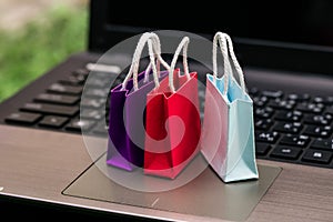 Three colorful paper shopping bags on laptop keyboard. Ideas about online shopping. e-commerce or electronic commerce is