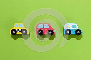 Three colorful wooden toy cars on green background