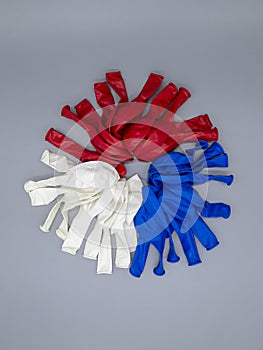 Three colors of deflated latex balloons white blue red on a gray background